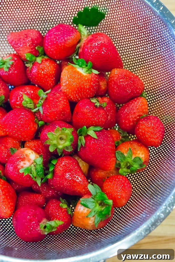 Overhead shot of the strawberry cobbler in a deep-dish pie plate, showing the rustic biscuit wedges and glistening jam.