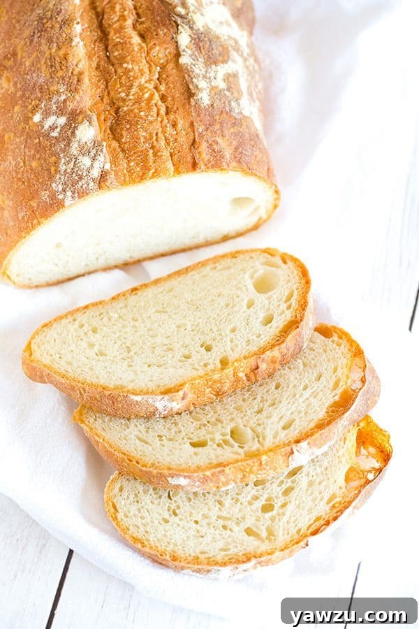A close-up of a perfectly buttered slice of rustic Italian bread, highlighting its soft crumb.