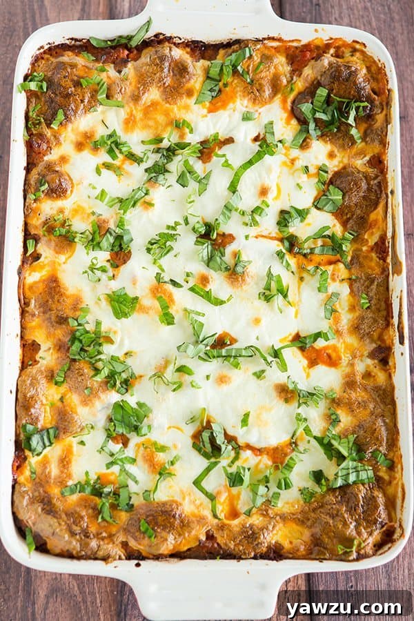 Close-up of a generous slice of Italian Pastitsio, showcasing the distinct layers of pasta, pink creamy meat sauce, and melted cheese.