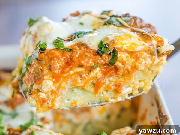 The layering process of the Italian Pastitsio in a baking dish, showing the spaghetti base, followed by the creamy white cheese layer.