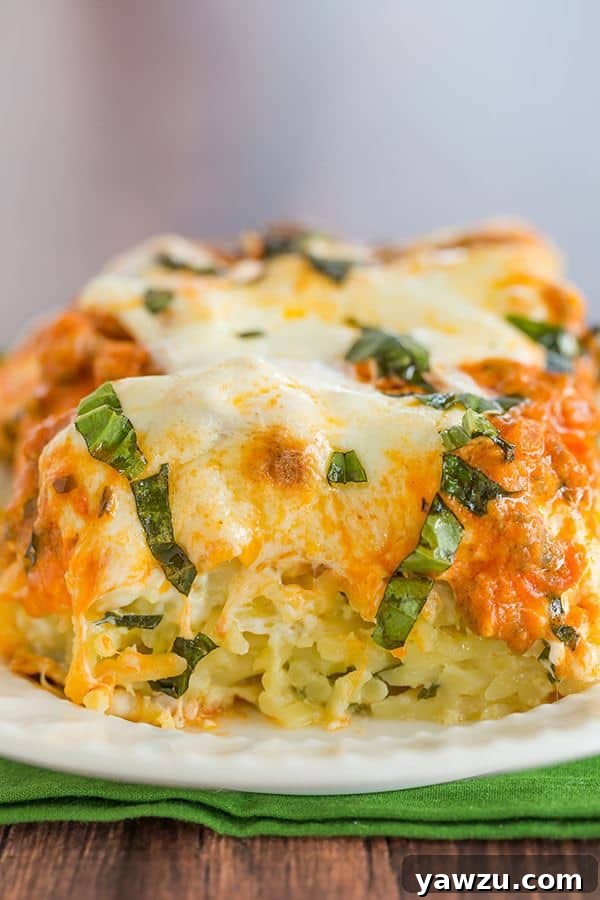 A close-up of the Italian Pastitsio, freshly baked with a golden-brown mozzarella topping and fresh basil leaves, ready to be served.