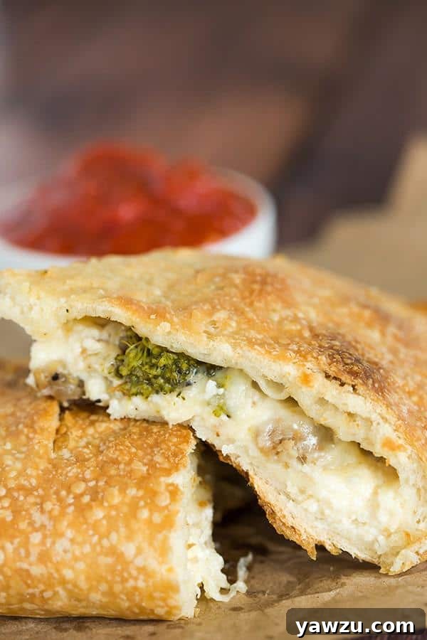 Cross-section of a baked calzone revealing melted cheese and fillings