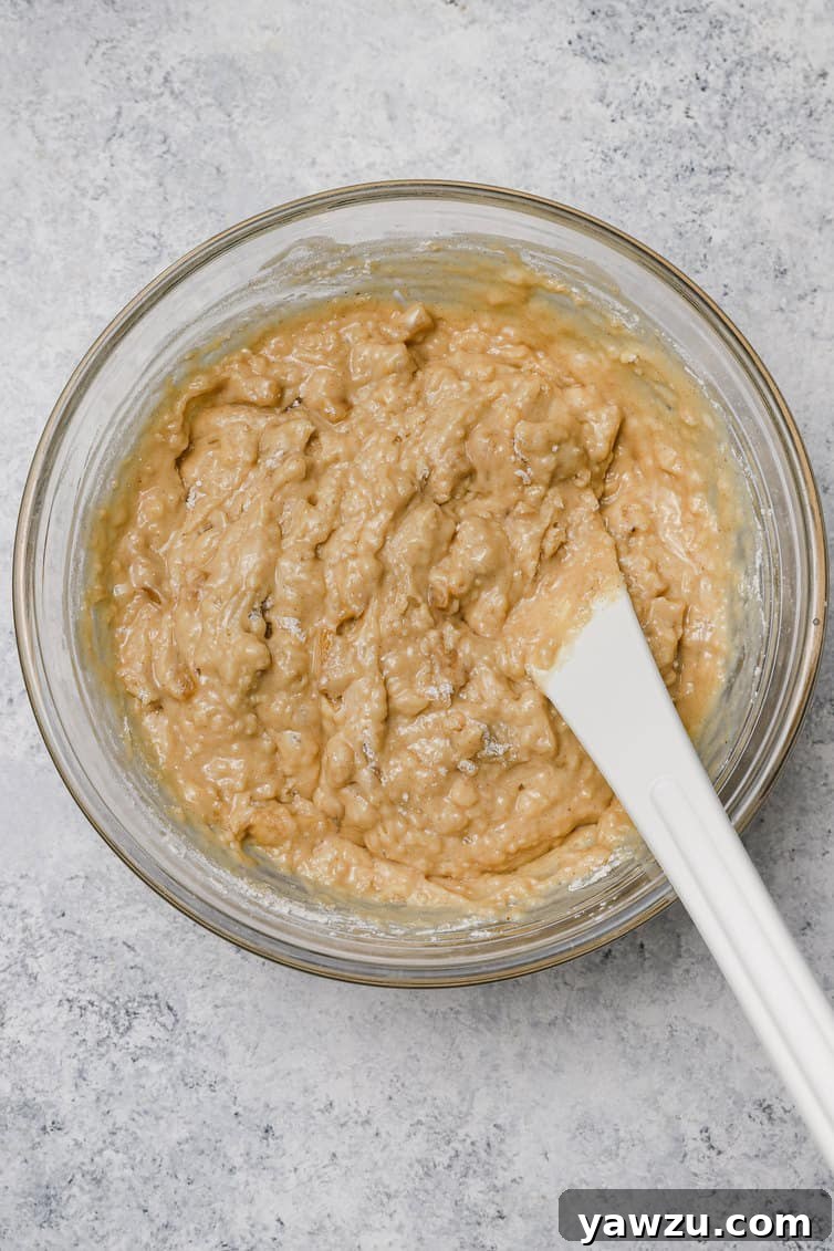 Apple muffin batter mixed together in a glass bowl.