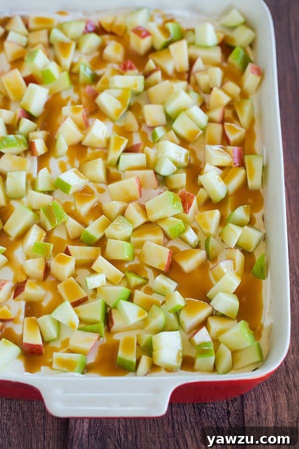 This caramel apple pudding has layers of caramel cheesecake filling, caramel pudding, a whipped cream topping, apples, and peanuts all on top of a gingersnap crust.