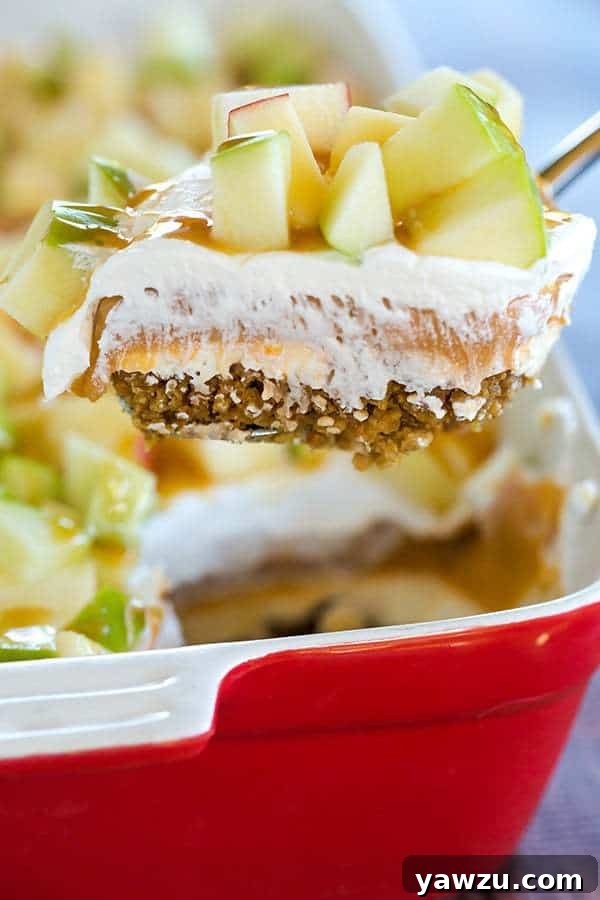 This caramel apple pudding has layers of caramel cheesecake filling, caramel pudding, a whipped cream topping, apples, and peanuts all on top of a gingersnap crust.
