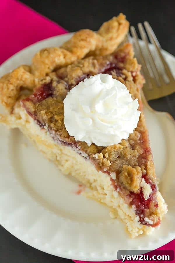 A slice of Cranberry Cheesecake Crumb Pie showcasing its distinct layers: golden pie crust, creamy cheesecake, bright red cranberry sauce, and a generous crumb topping.