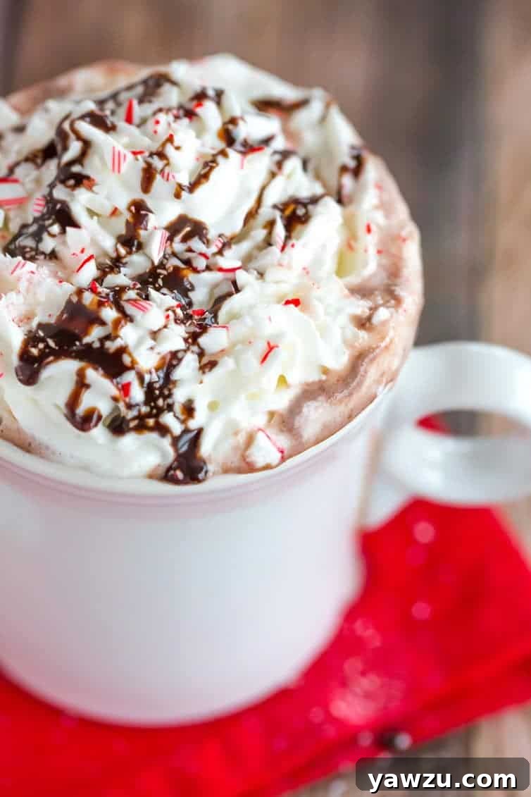 Rich Peppermint Bark Hot Chocolate topped with a swirl of whipped cream and a generous sprinkle of crushed candy canes, served in a rustic mug, perfect for cozy winter evenings.