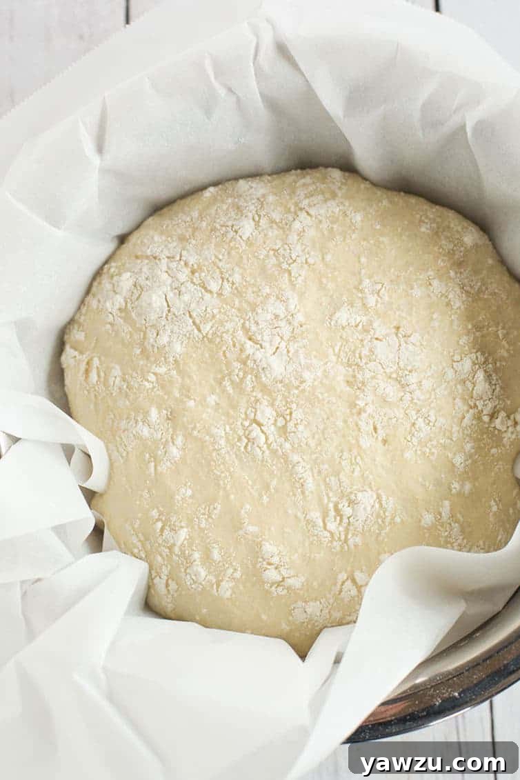 No-knead bread dough carefully placed on parchment paper, ready to be transferred to a hot Dutch oven.