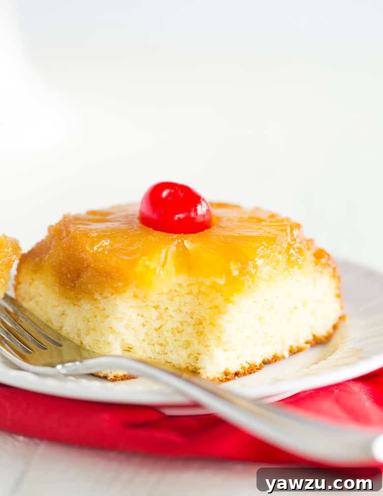 A close-up of a slice of pineapple upside down cake with a small bite taken out, showing the tender cake and juicy pineapple.