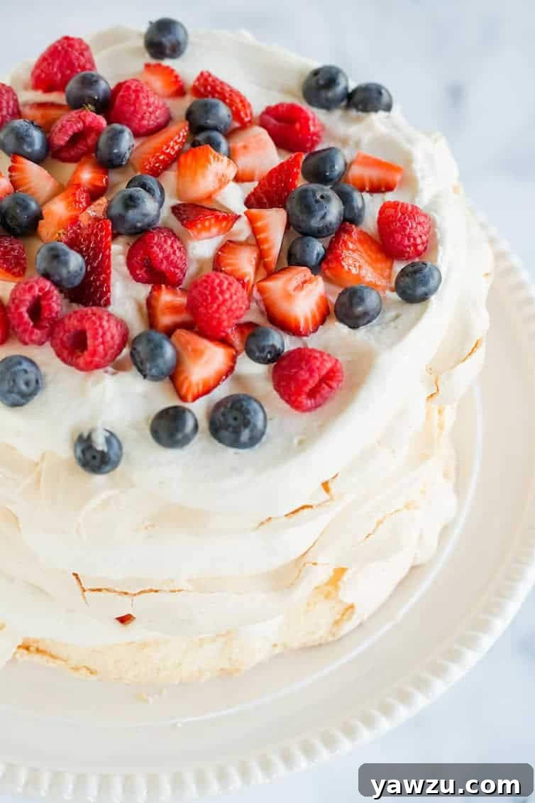An overhead view of a beautiful pavlova layer cake, adorned with whipped cream and an abundance of fresh berries.