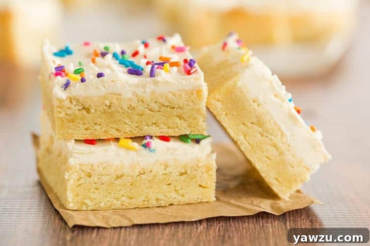Three perfectly frosted sugar cookie bars, each adorned with a generous layer of vanilla buttercream and festive sprinkles.