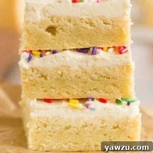 A stack of three sugar cookie bars with frosting and sprinkles.