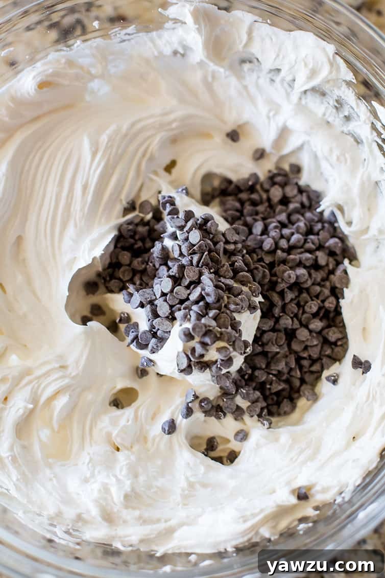 A close-up shot of perfectly whipped, glossy meringue, studded with mini chocolate chips, ready for baking.