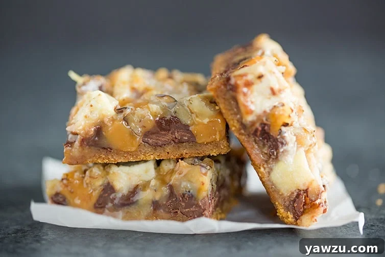 A close-up side view of baked caramel apple magic bars, revealing their delicious layers.