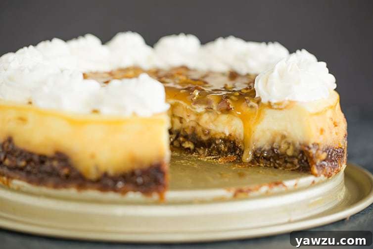 A whole pecan pie cheesecake with one slice expertly removed, showing the internal layers.