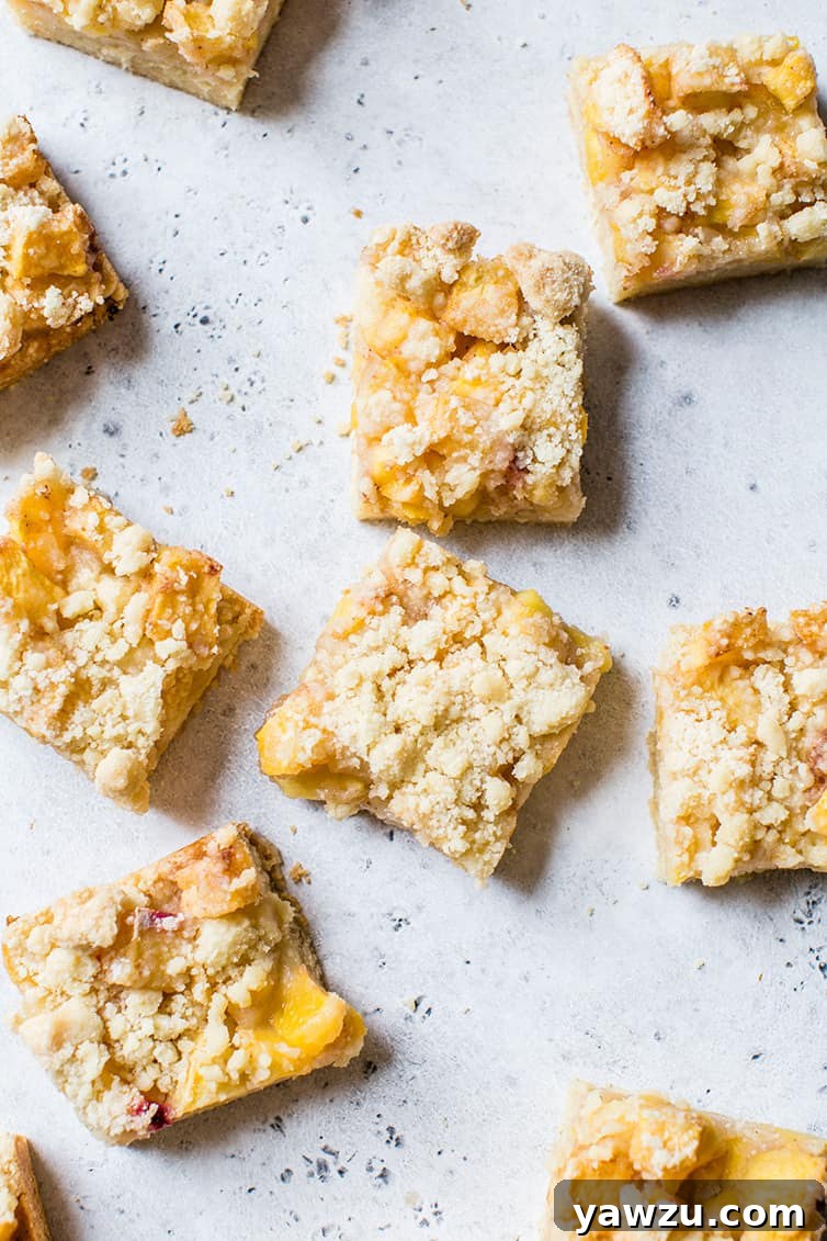 Freshly baked and cooled peach crumb bars, neatly cut and arranged on a serving platter.
