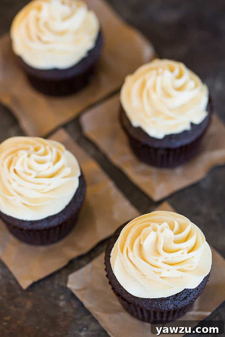 An inviting overhead shot showcasing four beautifully frosted chocolate cupcakes, adorned with a swirl of creamy vanilla frosting.