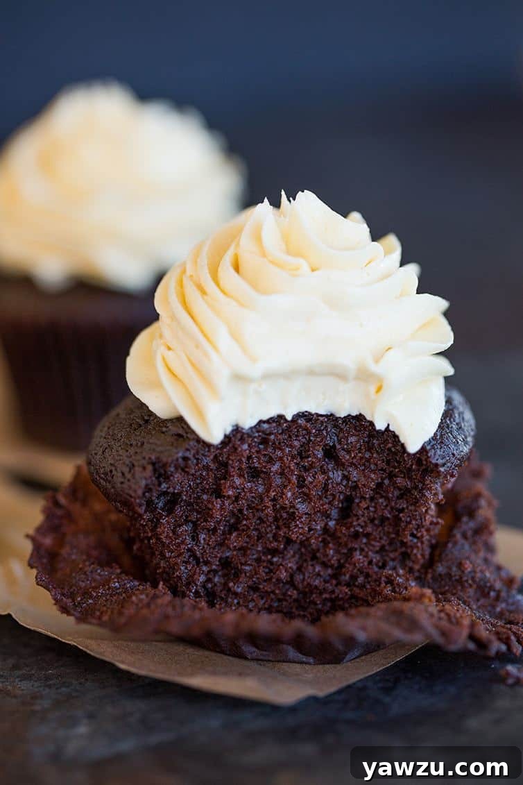 A delectable chocolate cupcake, generously frosted with vanilla buttercream, with a perfect bite taken out, revealing its rich interior.