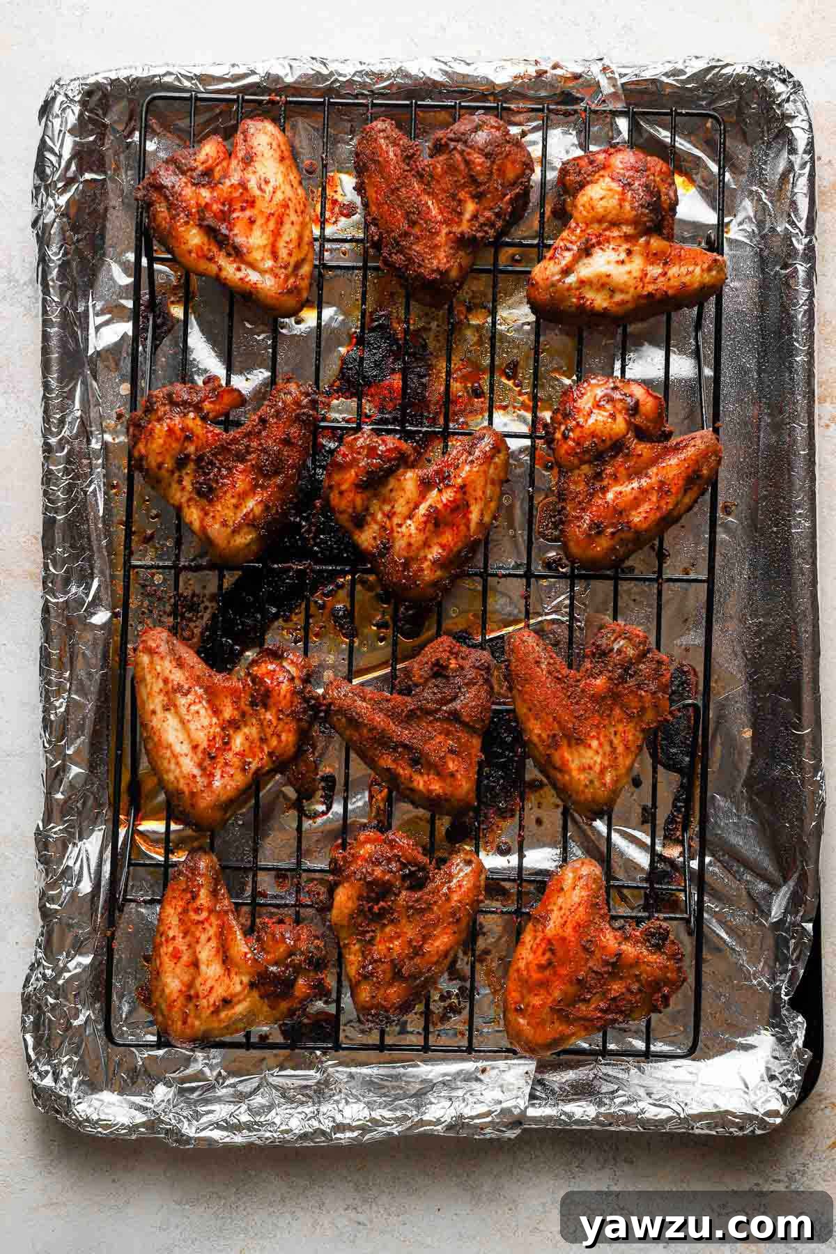 Crispy baked chicken wings neatly arranged on a wire rack set within a baking sheet, showcasing their golden-brown perfection.