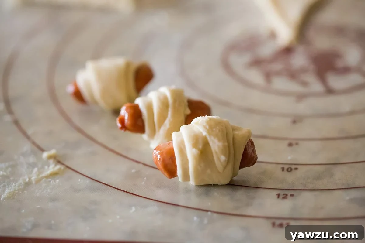 Mini hot dogs expertly rolled up in crescent roll dough, showcasing the perfect wrap.