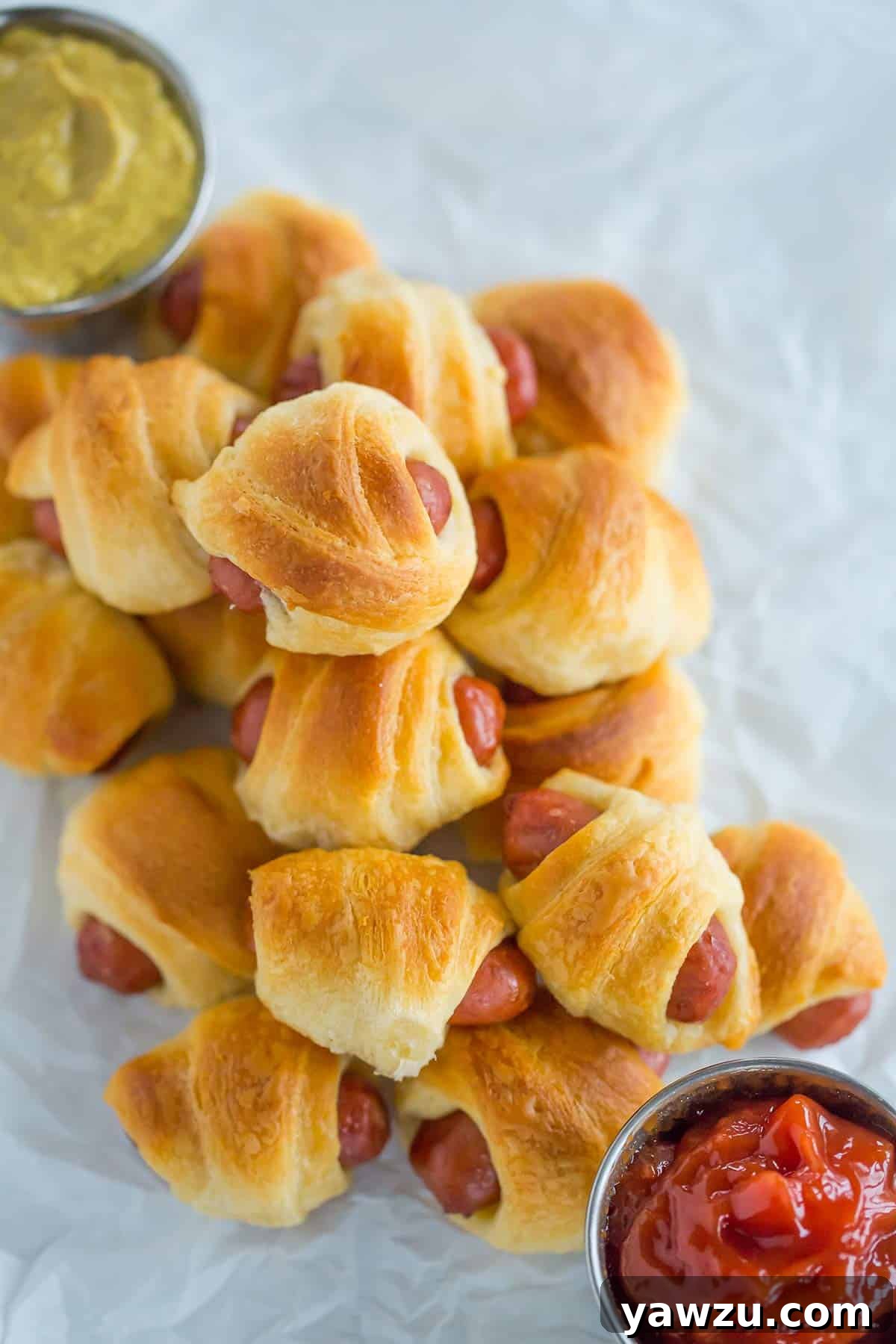 An overhead shot of mini hot dogs wrapped in crescent roll dough, baked to a perfect golden color.