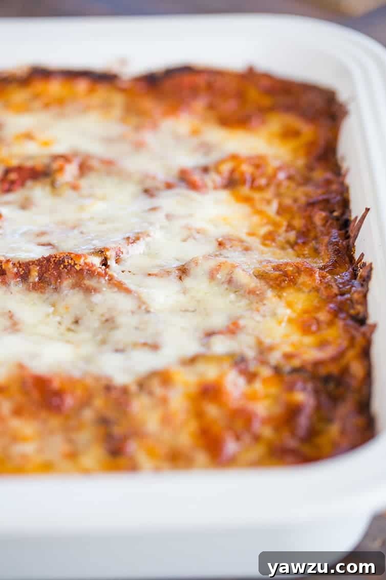 A pan of freshly baked eggplant parmesan, golden brown and bubbling, removed from the oven.