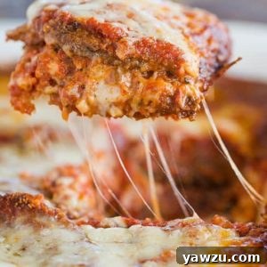 A slice of eggplant parmesan being lifted out of the pan.