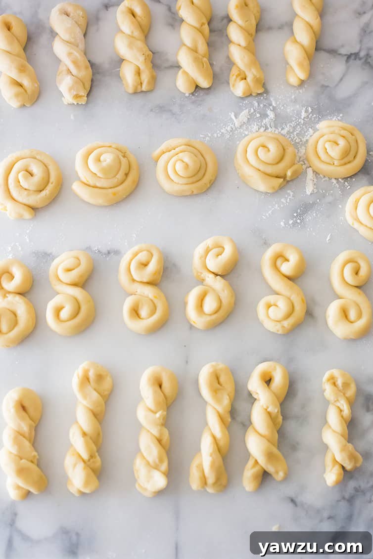 Shaped Koulourakia cookies on a marble pastry board.