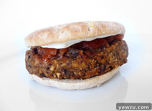 A delicious black bean mushroom burger on a toasted bun, topped with melted cheese and a swirl of ketchup, ready to be enjoyed.