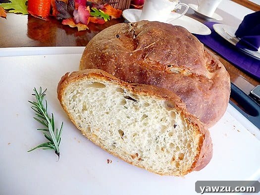 A freshly cut slice of potato rosemary bread with a perfect crumb, next to the full loaf on a wooden board, ready for serving.