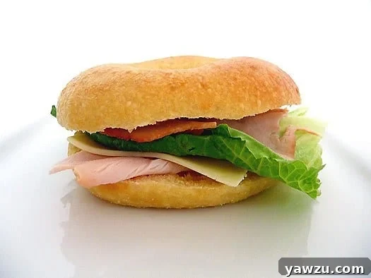 Egg bagel sandwich with lunch meat, slice of cheese, and lettuce.