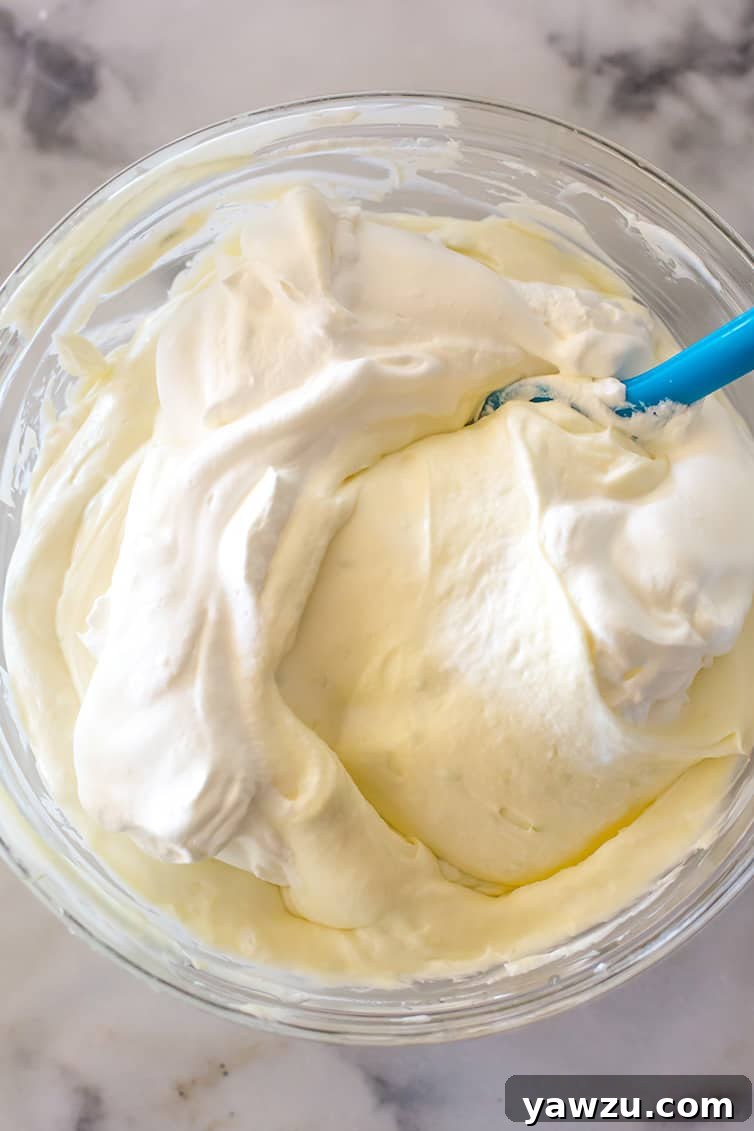 Folding heavy cream into the key lime cheesecake mixture.