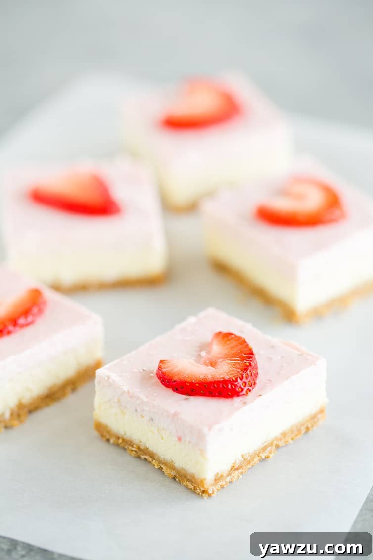 Five strawberry cheesecake bars arranged neatly on a piece of parchment paper, highlighting their delicious layers.
