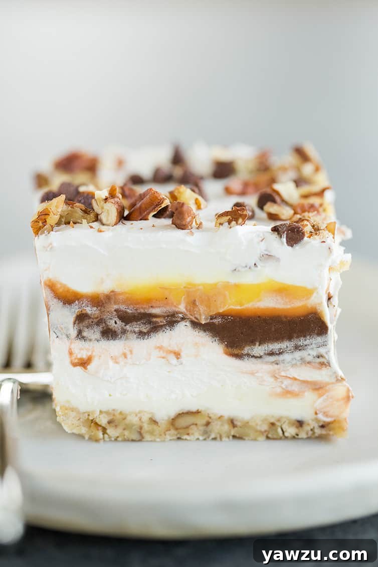 A piece of chocolate lush dessert on a plate with a fork, showing distinct layers.