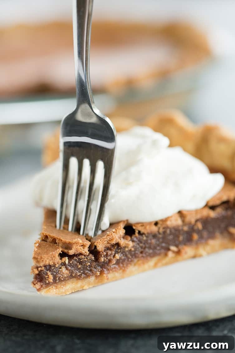 A close-up shot of a slice of chocolate chess pie with a fork gently piercing its rich, fudgy filling.