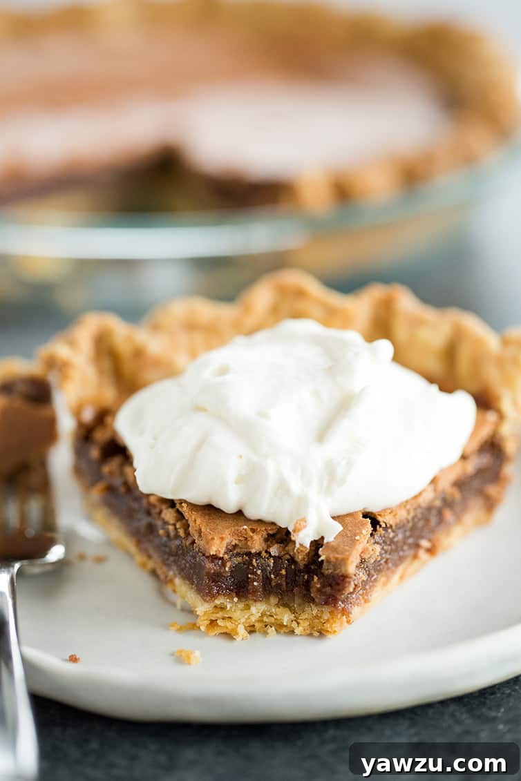 A slice of chocolate chess pie with a portion taken out, revealing the fudgy interior and crackled top.