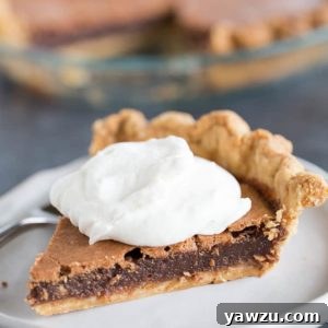 A slice of chocolate chess pie with whipped cream on top, and the full pie in the background.