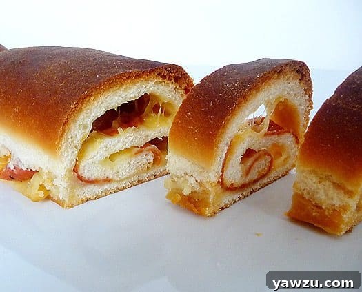 Several slices of freshly baked soft cheese and pepperoni bread arranged neatly on a pristine white plate, showcasing the golden crust and enticing swirled interior.