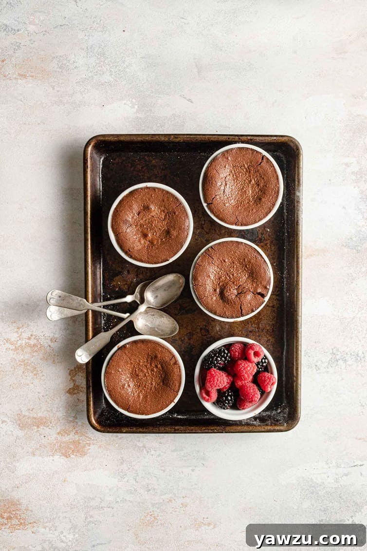 A baking sheet with four ramekins of baked chocolate lava cakes.