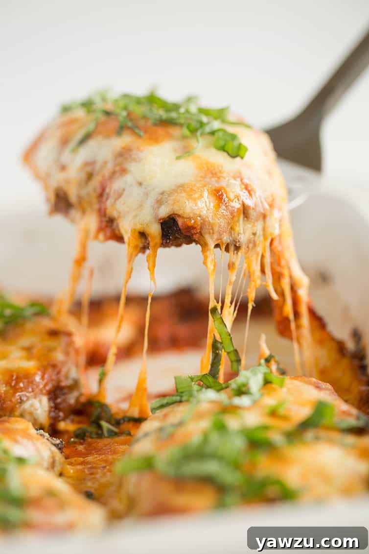 A piece of chicken parmesan being lifted out of the pan, showcasing its golden crust and melted cheese.