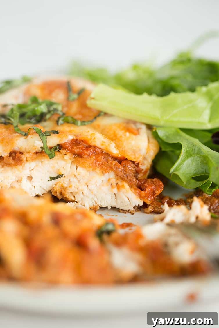 A perfectly sliced piece of chicken parmesan, revealing the layers of crispy chicken, sauce, and melted cheese.