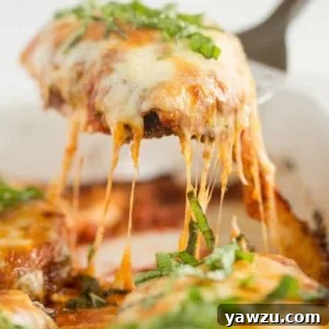 A piece of chicken parmesan being lifted out of the pan, showing its golden crust and melted cheese.