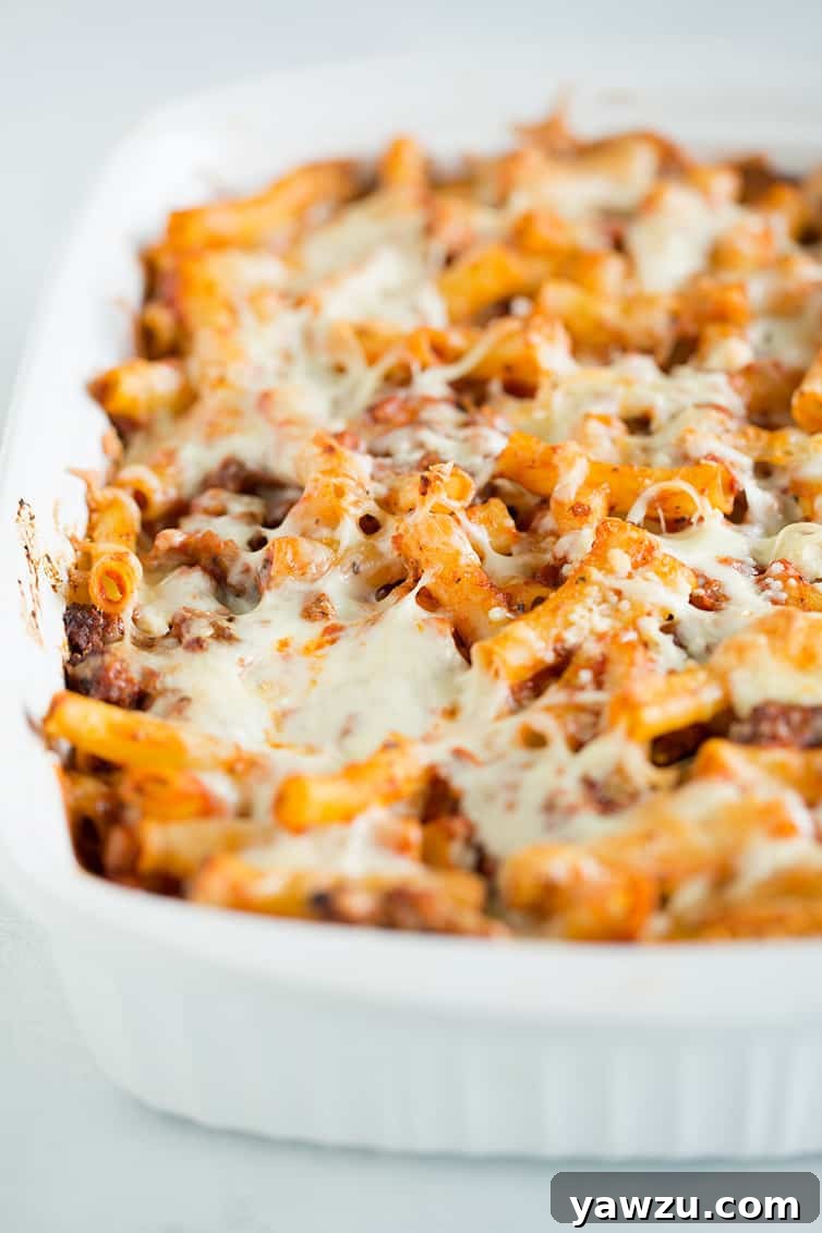 A large, rectangular casserole pan filled with golden-brown, bubbly baked ziti, ready to be served.
