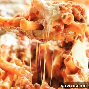 A spoonful of baked ziti being scooped out the pan.