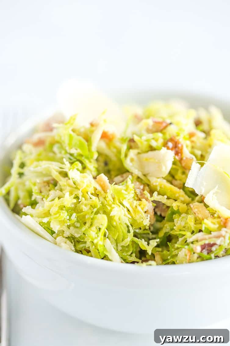 A bowl of Brussels sprouts salad with bacon, pecans and Parmesan cheese.