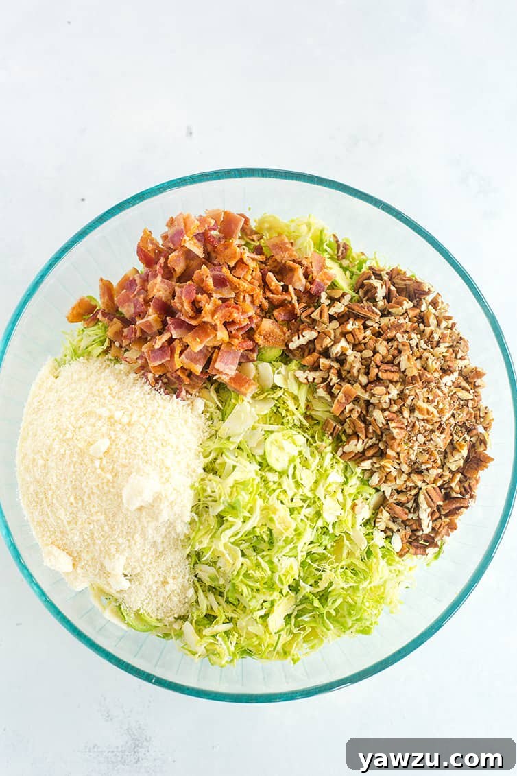A bowl with shaved Brussels sprouts, chopped bacon, chopped pecans, and Parmesan cheese.