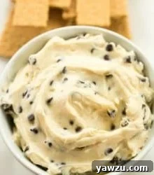A small bowl of Chocolate Chip Cookie Dough Dip with a spoon, highlighting its texture.