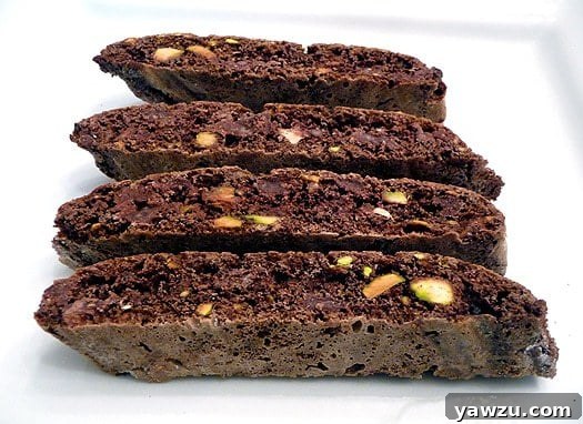 4 pieces of chocolate pistachio biscotti on a white plate.