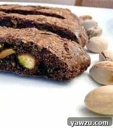 3 slices of chocolate pistachio biscotti on a white plate.