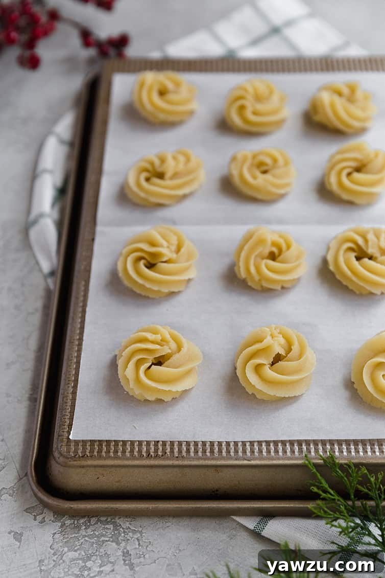 Danish butter cookies piped onto parchment paper, ready to be baked.